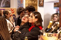 a group of people at a party with bottles of wine