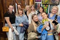 a group of women posing for a photo in an art gallery